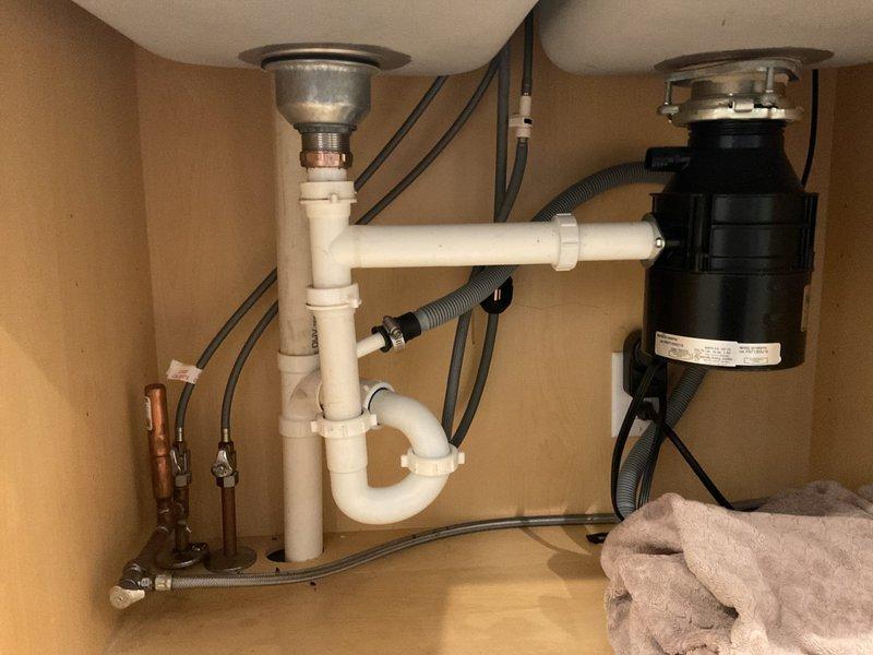 Responded to service call for drain backflow affecting both basins of kitchen double sink. Upon inspection, identified blockage in shared drain line causing water to back up into both sink compartments. Cleared obstruction from main drain line beneath sink cabinet, restoring proper drainage flow through P-trap assembly and disposal connection. Tested both basins under full water flow to verify complete drainage function and confirmed no further backflow issues. System operating normally upon completion.