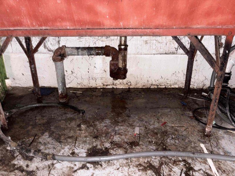 Responded to sump pump overflow emergency at residential property. Upon arrival, exercised caution due to presence of dogs on premises. Conducted thorough inspection of sump pump system and associated plumbing infrastructure in basement area. Documented existing conditions including deteriorated piping with significant corrosion on discharge lines and mounting assemblies. Assessed PVC drainage system routing through crawl space, noting accumulated debris and compromised connections. Identified primary cause of overflow as failed discharge mechanism combined with aged, corroded piping requiring immediate attention. Cleared obstruction from pump basin, tested pump operation, and verified proper cycling. Recommended replacement of corroded metal discharge components with updated PVC system to prevent future failures. Captured photographic documentation of existing conditions for customer records and future reference.