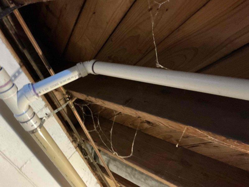 Responded to sump pump overflow emergency at residential property. Upon arrival, exercised caution due to presence of dogs on premises. Conducted thorough inspection of sump pump system and associated plumbing infrastructure in basement area. Documented existing conditions including deteriorated piping with significant corrosion on discharge lines and mounting assemblies. Assessed PVC drainage system routing through crawl space, noting accumulated debris and compromised connections. Identified primary cause of overflow as failed discharge mechanism combined with aged, corroded piping requiring immediate attention. Cleared obstruction from pump basin, tested pump operation, and verified proper cycling. Recommended replacement of corroded metal discharge components with updated PVC system to prevent future failures. Captured photographic documentation of existing conditions for customer records and future reference.