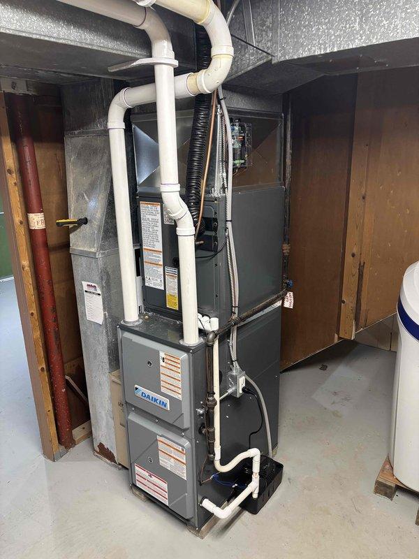 Completed full HVAC system replacement including installation of new Daikin furnace in basement mechanical room with updated white PVC venting and condensate drainage, connected to new air handler unit via flexible ductwork. Installed new outdoor condenser unit on concrete pad against exterior wall with proper electrical disconnect, conduit routing, and refrigerant line connections. All components tested and operational, system commissioned and ready for service.
