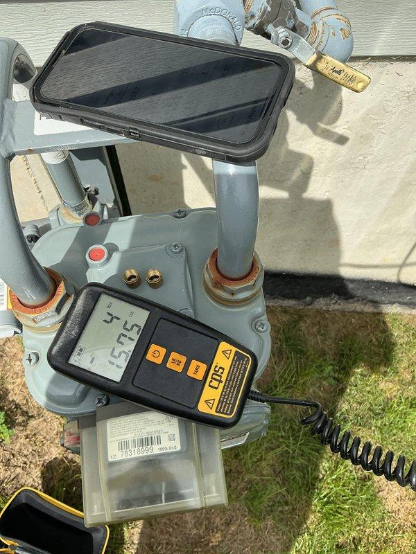 # CP-Cooling Problem - Rheem System

Responded to callback for 4-year-old Rheem system blowing warm air. Upon arrival, unit was shut down by customer due to lack of cooling. Performed diagnostic testing with digital gauges, which revealed abnormal temperature and pressure readings (37.2°F and 157.5 PSI observed on measurement device). Inspected outdoor condensing unit and associated components, noting corrosion present at pipe connection points. Evaluated refrigerant lines, expansion tank, and electrical connections. Documented system conditions with photos showing equipment layout, measurement readings, and overall installation. System required further assessment of refrigerant charge levels and potential leak points based on gauge readings and warm air complaint consistent with recent service history.