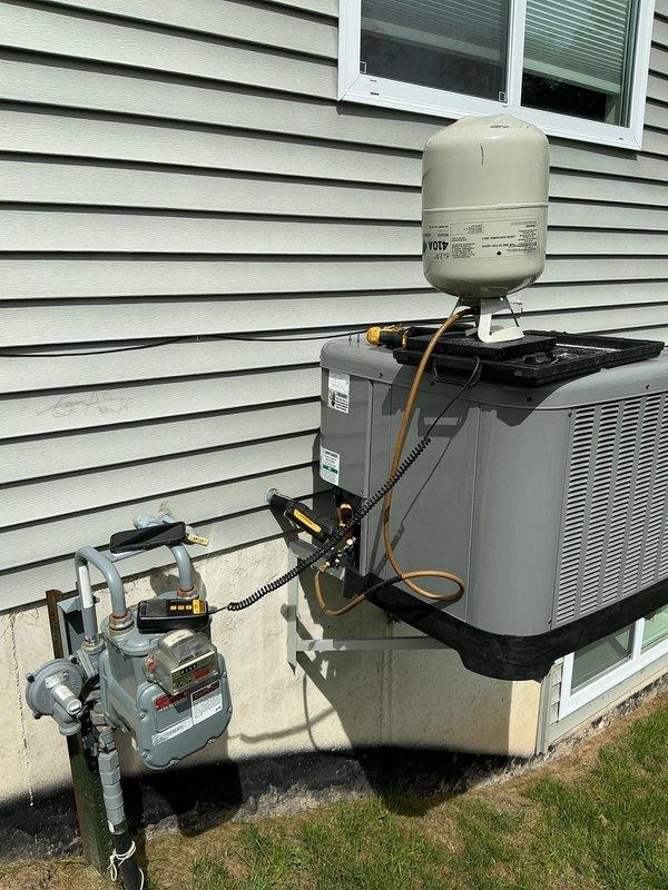 # CP-Cooling Problem - Rheem System

Responded to callback for 4-year-old Rheem system blowing warm air. Upon arrival, unit was shut down by customer due to lack of cooling. Performed diagnostic testing with digital gauges, which revealed abnormal temperature and pressure readings (37.2°F and 157.5 PSI observed on measurement device). Inspected outdoor condensing unit and associated components, noting corrosion present at pipe connection points. Evaluated refrigerant lines, expansion tank, and electrical connections. Documented system conditions with photos showing equipment layout, measurement readings, and overall installation. System required further assessment of refrigerant charge levels and potential leak points based on gauge readings and warm air complaint consistent with recent service history.