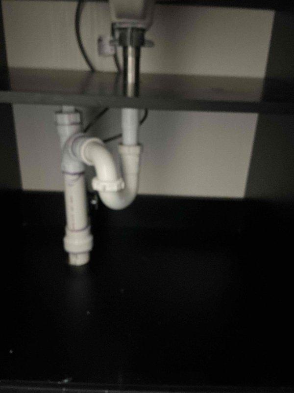 Completed repipe of sewage ejection pit discharge line, installing new PVC drainage system with proper P-trap configuration and secure connections. Replaced kitchen sink faucet assembly including supply lines and drain components, ensuring proper water flow and leak-free operation throughout the installation.