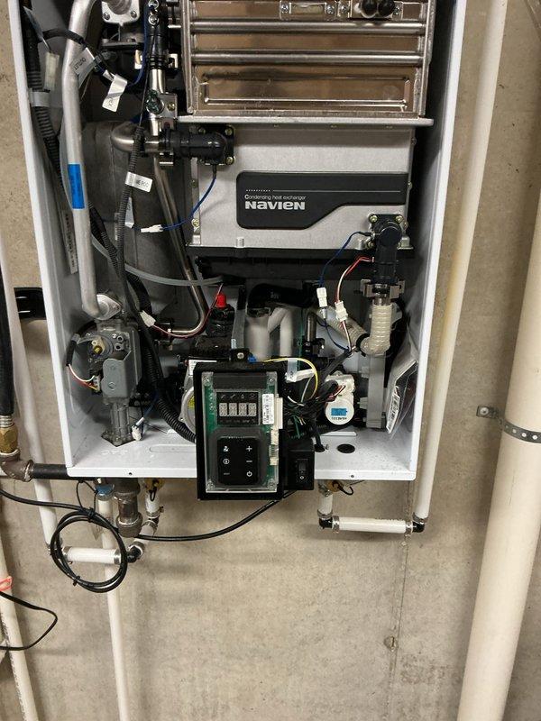 Responded to service call for leaking Navien tankless water heater approximately 6-8 years old. Upon inspection, removed front access panel and performed diagnostic assessment of internal components including circulation pump, heat exchanger assembly, water connections, and condensate drainage system. Identified source of leak and documented internal component condition with detailed photographs showing pump assembly, plumbing connections, and overall unit configuration for warranty and repair reference purposes.