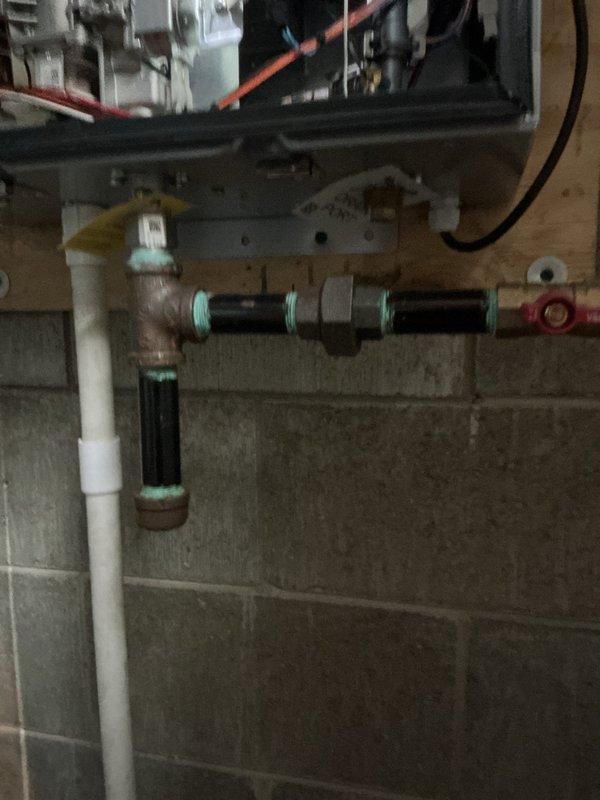 Completed comprehensive tune-up service on tankless water heater system approximately 6 years old. Performed standard maintenance procedures including descaling of heat exchanger, inspection of all electrical connections and components visible within control housing, verification of proper venting through white PVC exhaust piping, and testing of water supply lines with isolation valves. All mechanical components including internal fan assembly and control board were inspected and found to be functioning within normal parameters.