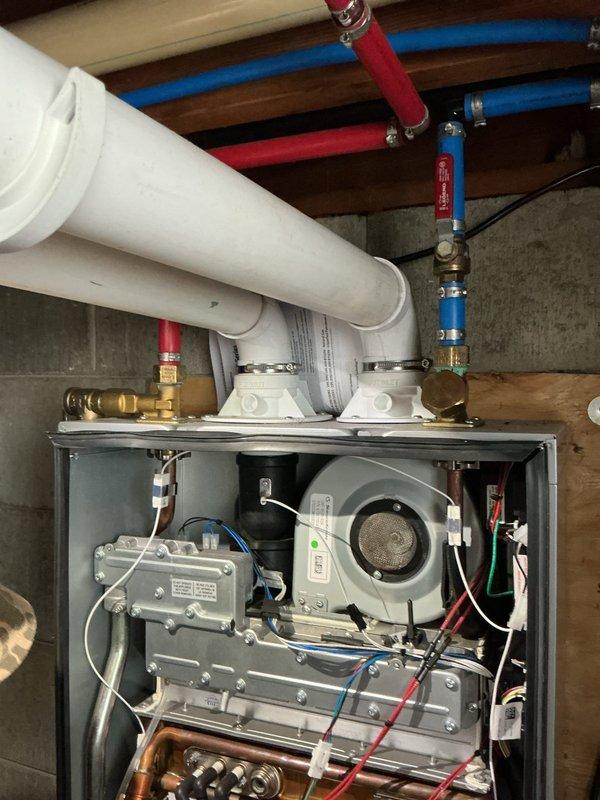 Completed comprehensive tune-up service on tankless water heater system approximately 6 years old. Performed standard maintenance procedures including descaling of heat exchanger, inspection of all electrical connections and components visible within control housing, verification of proper venting through white PVC exhaust piping, and testing of water supply lines with isolation valves. All mechanical components including internal fan assembly and control board were inspected and found to be functioning within normal parameters.