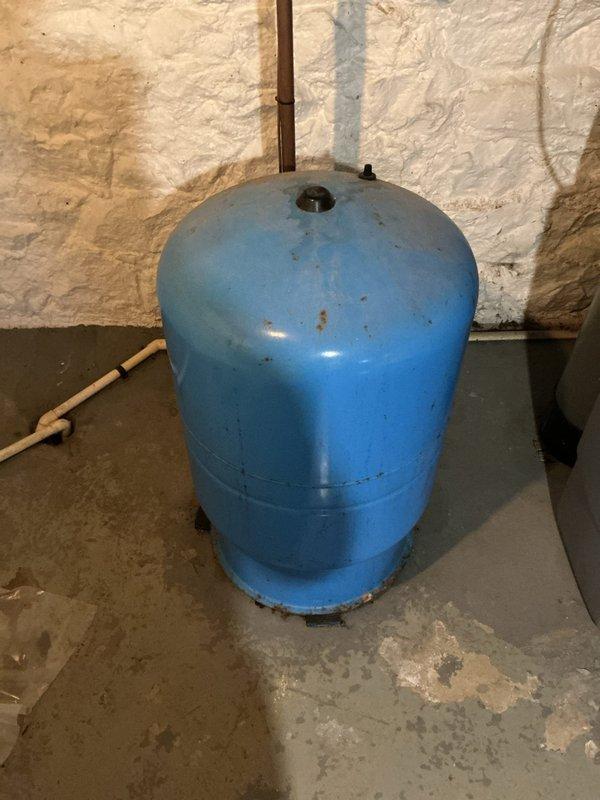 Responded to service call for water leak from pressure tank resulting in loss of water supply. Upon inspection, found 20-year-old blue pressure tank with visible signs of age, corrosion, and deterioration including rust spots on upper portion and worn paint around seams and base. Tank exhibited active leak requiring immediate attention. Documented existing conditions with photos showing corroded tank, copper piping connections, and water damage evidence on concrete floor. Completed work order and provided client with assessment of aging pressure tank system.