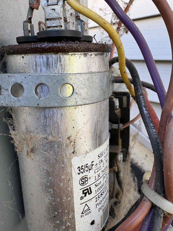 Completed annual cooling maintenance on 19-year-old Goodman air conditioning system. Performed comprehensive inspection revealing dual-rated capacitor (35/5µF) showing signs of age with surface oxidation and weather exposure, though still within operational parameters. Electrical connections at contactor assembly examined and found secure despite visible environmental wear. Cleaned extensive cobweb accumulation and debris from control panel area, electrical connections, and equipment base to prevent potential airflow restriction and ensure proper heat dissipation from electrical components. Verified all wire terminations at terminal blocks and contactor remain tight and functional. System tested and confirmed operational for continued service.