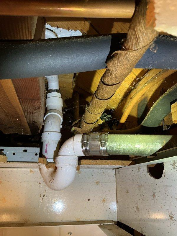 Conducted plumbing project estimate for mixing valve replacement. Inspected under-sink plumbing area and basement utility room to assess condition of water supply lines and identify source of corrosion. Documented existing plumbing infrastructure including copper supply lines, PVC drainage system, and mixing valve assembly with visible green corrosion spots indicating potential brass dezincification or copper oxidation. Photographed affected piping, valve configuration, and surrounding plumbing components to provide comprehensive assessment for valve replacement project and any necessary supply line repairs.