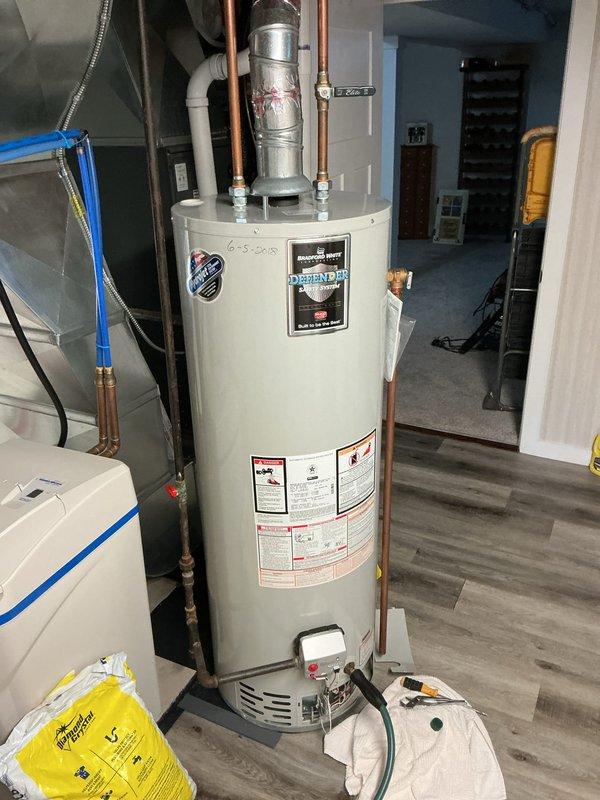 Provided estimate for replacement of existing 40-gallon water heater with Bradford White 40-gallon gas water heater. Current unit is a Bradford White model located in basement utility area with copper supply lines and flexible connectors. Customer will supply drip pan for installation with new unit.