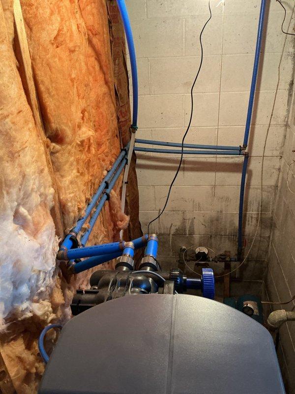 Performed on-site evaluation for water softener replacement estimate at residential property. Inspected existing Culligan water conditioning system currently installed in utility closet with adequate plumbing infrastructure including copper supply lines, brass fittings, and PVC drain configuration. System operational with digital control panel functioning properly and salt supply present. Assessed installation location featuring white tile walls, concrete flooring, and sufficient clearance for equipment access and maintenance. Documented existing plumbing layout including vertical and horizontal blue PVC piping network, connection points on concrete block wall, and proximity to water heater. Photographed current system configuration, utility room conditions, and available workspace for potential replacement installation. Reviewed customer interest in alternative water conditioning solutions and service options compared to current provider.