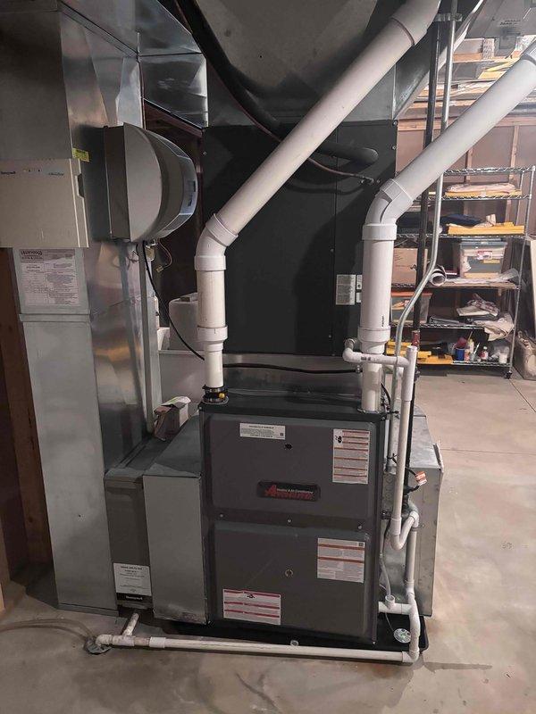 Completed full furnace installation in basement mechanical room. Installed new dark gray furnace unit with proper venting system using white PVC piping for exhaust and intake, routed to exterior. Connected metallic air handler component and integrated black flexible ductwork with existing rectangular metal ductwork for proper air distribution throughout the residence. Secured all electrical connections, plumbing lines, and ensured proper clearances around equipment. Verified all manufacturer specifications met, system operational, and heating functionality tested successfully.