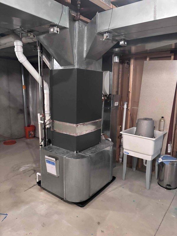 Completed full furnace installation in basement mechanical room. Installed new dark gray furnace unit with proper venting system using white PVC piping for exhaust and intake, routed to exterior. Connected metallic air handler component and integrated black flexible ductwork with existing rectangular metal ductwork for proper air distribution throughout the residence. Secured all electrical connections, plumbing lines, and ensured proper clearances around equipment. Verified all manufacturer specifications met, system operational, and heating functionality tested successfully.