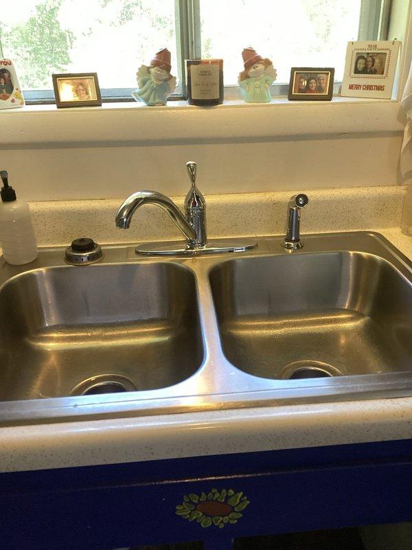 Responded to service call for leaking kitchen faucet in residential property. Upon inspection, identified active leak at faucet base with visible water damage and staining in cabinet below sink, indicating ongoing moisture issue. Disassembled chrome single-lever faucet assembly, replaced worn internal cartridge and deteriorated O-rings causing the leak. Cleaned and reassembled faucet components, tested water flow and spray nozzle function, confirmed leak elimination with no dripping at base or connections. Verified all supply line connections under sink were secure and dry upon completion.