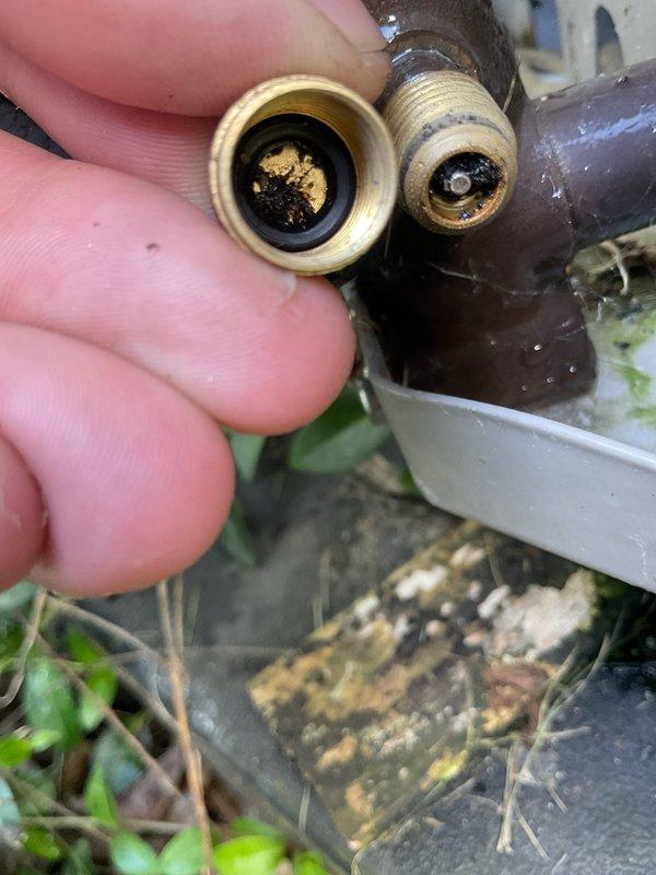 Completed annual cooling maintenance on 9-year-old Bryant air conditioning system. Inspected and cleaned brass hose connectors which showed significant accumulation of black residue and sediment buildup. Removed debris from threaded fittings and connection points to ensure proper water flow and system efficiency.
