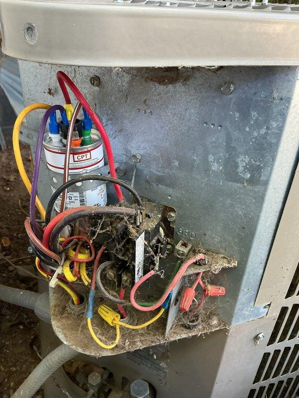 # CP-Cooling Problem Resolution

Responded to service call for 10-year-old air conditioning system that had tripped the circuit breaker and exhibited cooling performance issues. Upon arrival, conducted comprehensive inspection of outdoor condenser unit and electrical components.

Removed and inspected electrical compartment, revealing significant corrosion and deterioration on contactor assembly with visible rust staining throughout the panel. Identified heavily corroded contactor as primary failure point causing electrical overload and breaker trip. Capacitor showed signs of age but terminals remained intact with proper wire connections in place.

Cleaned electrical compartment of accumulated dirt, debris, and corrosion. Replaced failed contactor with new unit, ensuring all wire connections—including yellow, red, purple, blue, orange, and ground wires—were properly terminated and secured. Verified capacitor functionality and all electrical connections for integrity.

Tested system ope