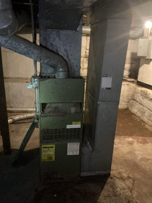 Provided estimate for replacement of 35-year-old standard tank water heater originally manufactured in 1991. Unit has reached end of expected service life and requires full replacement. Documented existing installation conditions in unfinished basement area with photographic records showing structural support elements, mechanical systems layout, and current equipment placement for accurate replacement planning.