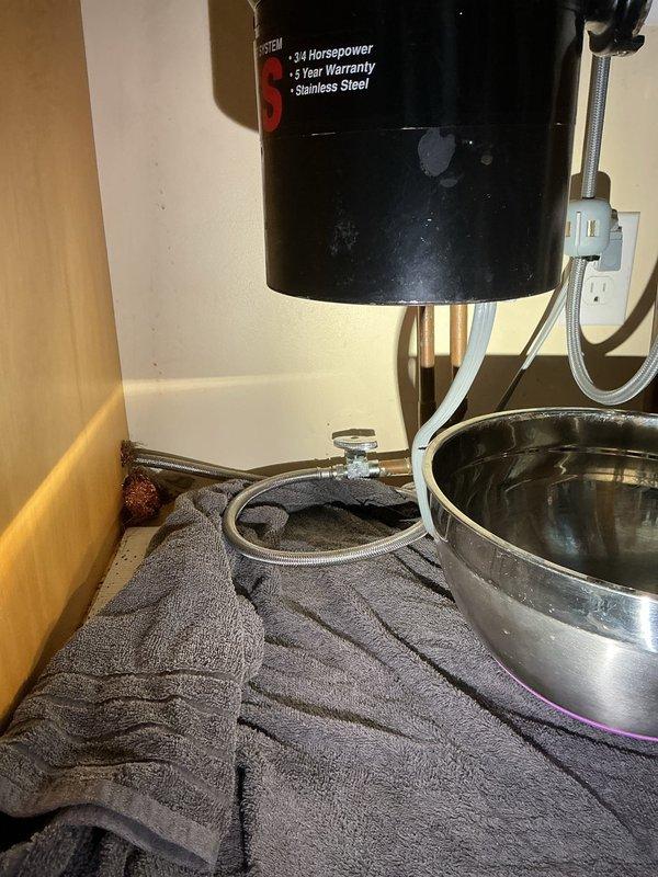 Responded to emergency water leak under kitchen sink caused by broken dishwasher shutoff valve with hot water actively discharging from disconnected supply line. Shut off main water supply to house to stop flooding, replaced faulty shutoff valve, reconnected dishwasher supply line with new braided stainless steel flex hose, and restored water service to residence after testing connections for leaks.