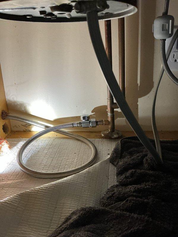 Responded to emergency water leak under kitchen sink caused by broken dishwasher shutoff valve with hot water actively discharging from disconnected supply line. Shut off main water supply to house to stop flooding, replaced faulty shutoff valve, reconnected dishwasher supply line with new braided stainless steel flex hose, and restored water service to residence after testing connections for leaks.