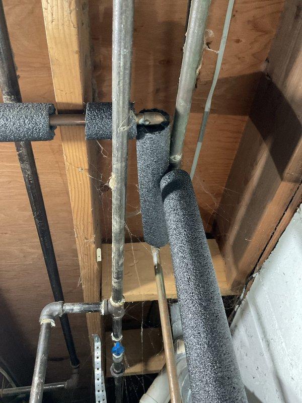 Completed annual cooling maintenance on 30-year-old Carrier system. Inspected basement mechanical area and documented condition of HVAC infrastructure including exposed piping with foam insulation running through wooden framing members. Observed significant water accumulation and pooling on basement floor near heating equipment, with brownish-yellow staining indicating ongoing moisture infiltration issues that could affect system performance and longevity. Photographed water damage patterns and standing water conditions for record. System operational at time of visit.