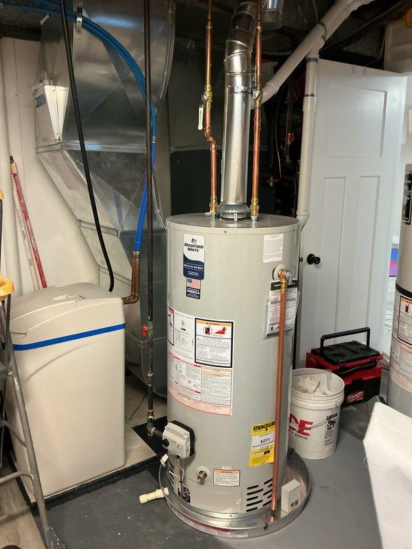 Installed a 40-gallon natural gas atmospheric vent water heater with 6-year warranty in residential utility room. Connected copper supply lines, stainless steel flue vent, and verified proper operation of all safety controls and temperature settings per manufacturer specifications.