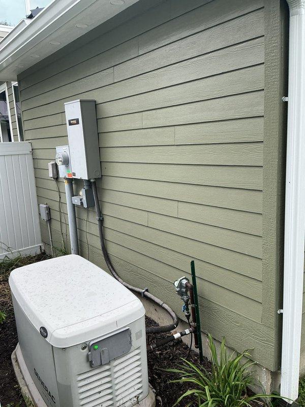 Completed on-site assessment for conversion of residential standby generator from liquid propane to natural gas fuel source. Evaluated existing generator installation, including current LP gas supply line configuration, electrical disconnect panel, and conduit routing along exterior wall. Inspected gas meter location and existing utility connections to determine feasibility of natural gas conversion.

Assessed required gas line routing from meter to generator location at rear of residence. Measured distance and documented obstacles including landscaping, mulched areas, and structural components. Identified optimal path for new gas line installation to minimize disruption to existing hardscape and plantings. Documented current plumbing infrastructure at building corner, including PVC piping, brass fittings, and existing valve assemblies to ensure proper clearances for new gas line routing.

Photographed all relevant equipment and utility connections for conversion estimate preparation. 