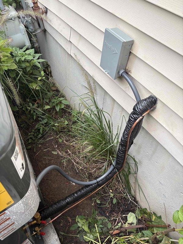 Completed full HVAC system replacement including outdoor condensing unit and indoor air handler/furnace. Removed existing equipment and installed new gray cabinet furnace unit in basement utility area with proper PVC intake and exhaust venting configuration. Mounted new outdoor heat pump/AC unit on concrete pad with proper clearances from building structure. Installed gray electrical disconnect box on exterior wall with code-compliant conduit routing to outdoor unit. Connected refrigerant lines between indoor and outdoor components using copper lineset. Verified all electrical connections, tested system operation, and confirmed proper airflow through ductwork connections.