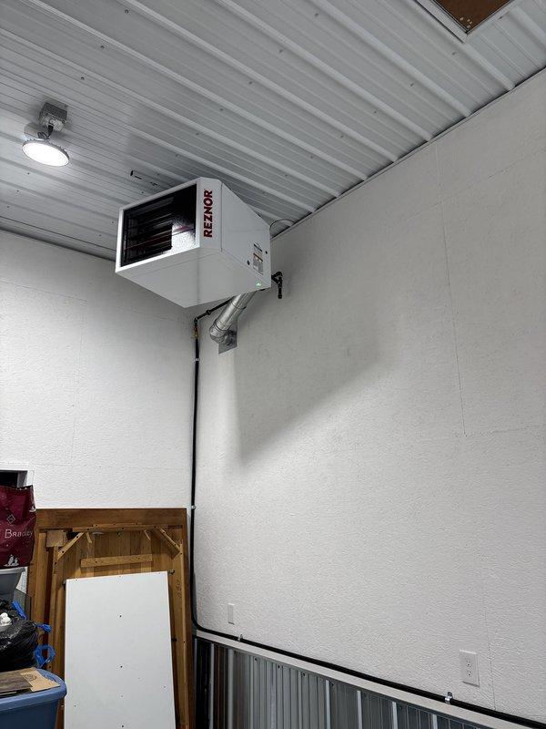 Installed new Reznor unit heater in commercial/warehouse space, mounting unit high on wall near ceiling corner. Completed electrical connections via conduit, verified proper operation of horizontal louver discharge system, and ensured heating unit functions correctly for the space.