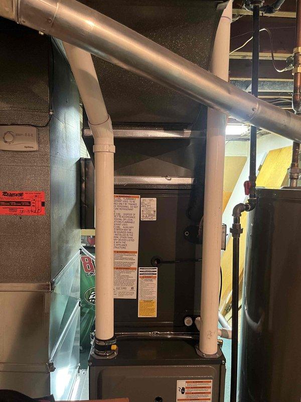 Completed full HVAC system installation including indoor air handler/furnace unit and outdoor condensing unit. Indoor equipment installed in mechanical room with proper ductwork connections, PVC condensate drainage, electrical connections, and ventilation. Outdoor condenser positioned on concrete pad with appropriate clearances, connected via electrical conduit, and surrounded by rock drainage bed for proper water management. All equipment labeled, secured, and tested for proper operation upon completion.