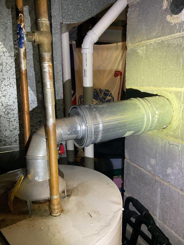 Responded to service call for leaking water heater estimated to be 15-20 years old. Performed comprehensive assessment of existing unit located in basement utility area, documenting condition through photographic evidence. Observed visible water damage and yellow staining on lower portion of tank exterior, indicating active leak from aging equipment. Evaluated all plumbing connections including copper supply lines, brass fittings, pressure relief valve, and drain valve assembly. Assessed surrounding infrastructure including PVC drainage, galvanized ductwork, and concrete block wall clearances. Provided detailed estimate for complete water heater replacement due to tank failure and age of existing unit beyond serviceable lifespan.
