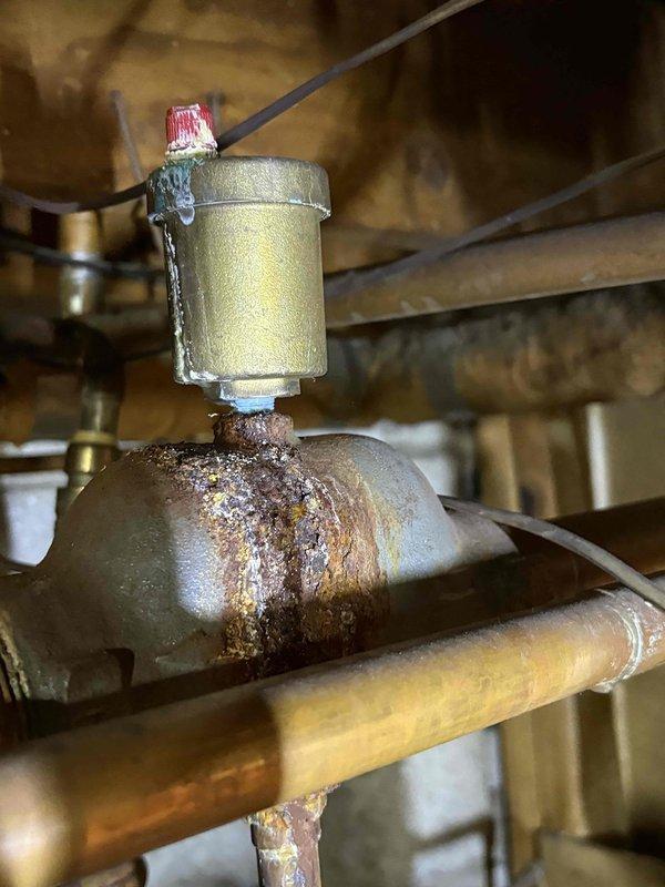 Responded to service call for 24-year-old Utica boiler experiencing small leak identified during home inspection prior to property sale. Upon arrival, inspected boiler system and located source of leak at corroded piping section beneath brass filter housing. Documented extensive rust and oxidation on affected pipe fitting, indicating prolonged moisture exposure and deterioration of ferrous metal components. Assessed overall condition of heating system and identified necessary repairs per home inspector's requirements to facilitate property closing. Photographed corroded areas and affected components showing compromised pipe integrity with heavy rust buildup on connections below filter assembly dated 9-16-26. Provided homeowner with detailed findings and repair recommendations to address leak and corrosion issues for real estate transaction completion.