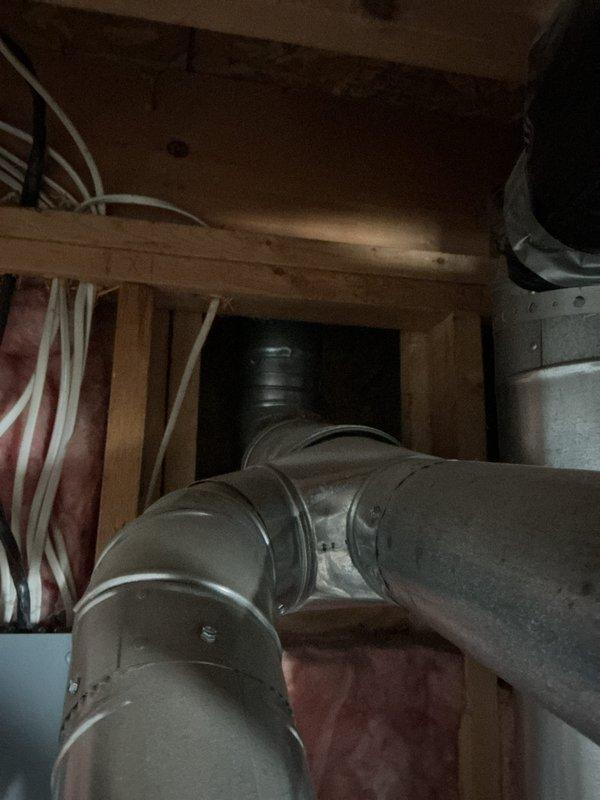Responded to service call for leaking water heater in residential basement utility area. Upon arrival, inspected 10-year-old water heater unit and surrounding plumbing connections, including copper supply lines, flexible connectors, and associated brass fittings. Documented existing installation configuration with water heater positioned against unfinished wall framing with exposed insulation. Photographed unit showing dark blue tank body with gray metal top section, multiple pipe connections, PVC/metal ductwork, flexible metallic gas connector, and safety valve components. Assessed leak source and overall system condition to provide customer with repair or replacement recommendations.