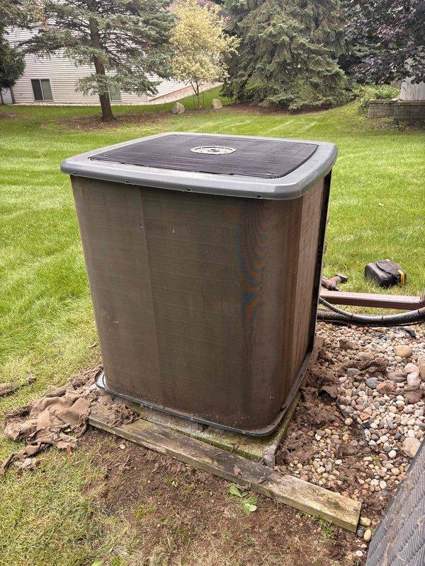 Completed annual cooling system maintenance and tune-up on residential air conditioning unit. Upon arrival, exterior condenser showed significant accumulation of dirt, dust, and debris on side panels with weathering and rust streaking visible on metal casing. Performed comprehensive inspection of outdoor condensing unit including assessment of refrigerant lines, electrical connections, and overall system condition. Documented pre-service condition showing heavy exterior soiling that could restrict airflow and reduce system efficiency. Unit positioned on concrete pad with proper clearances maintained in landscaping area. All safety protocols observed during maintenance procedure.