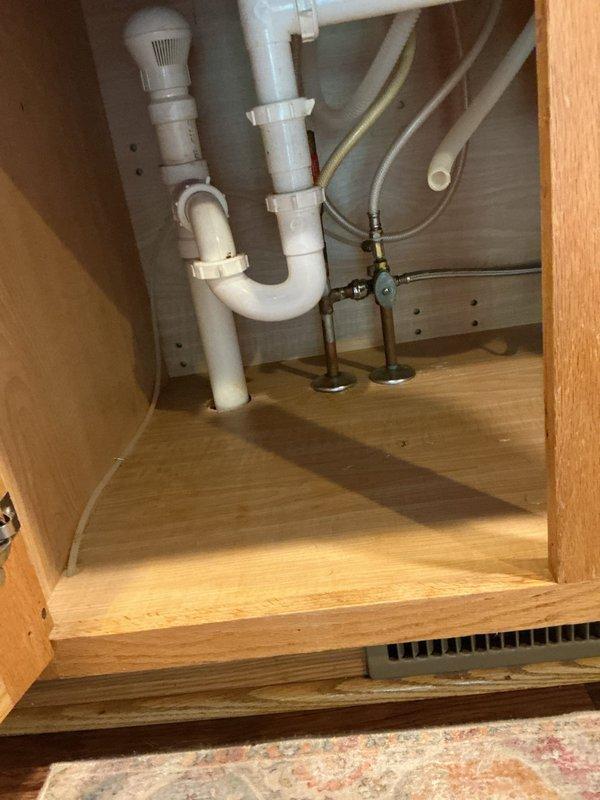 Responded to service call for low water pressure at kitchen faucet in single family residence. Upon arrival, accessed plumbing assembly beneath sink to diagnose issue. Inspected shut-off valves, supply lines, and faucet connections for restrictions or blockages. Found debris buildup in aerator and partially closed angle stop valve affecting flow rate. Removed and cleaned faucet aerator, adjusted angle stop valves to fully open position, and verified proper water pressure restoration at fixture. Tested hot and cold water flow to confirm adequate pressure and proper operation. Inspected braided supply lines and PVC drain assembly for leaks or damage - all components found to be in good working condition with no signs of corrosion or deterioration. Documented plumbing configuration with photographs for service records. System restored to normal operating pressure and function.