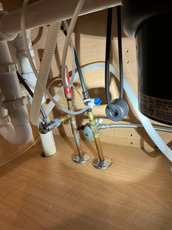 Responded to service call for low water pressure at kitchen faucet in single family residence. Upon arrival, accessed plumbing assembly beneath sink to diagnose issue. Inspected shut-off valves, supply lines, and faucet connections for restrictions or blockages. Found debris buildup in aerator and partially closed angle stop valve affecting flow rate. Removed and cleaned faucet aerator, adjusted angle stop valves to fully open position, and verified proper water pressure restoration at fixture. Tested hot and cold water flow to confirm adequate pressure and proper operation. Inspected braided supply lines and PVC drain assembly for leaks or damage - all components found to be in good working condition with no signs of corrosion or deterioration. Documented plumbing configuration with photographs for service records. System restored to normal operating pressure and function.