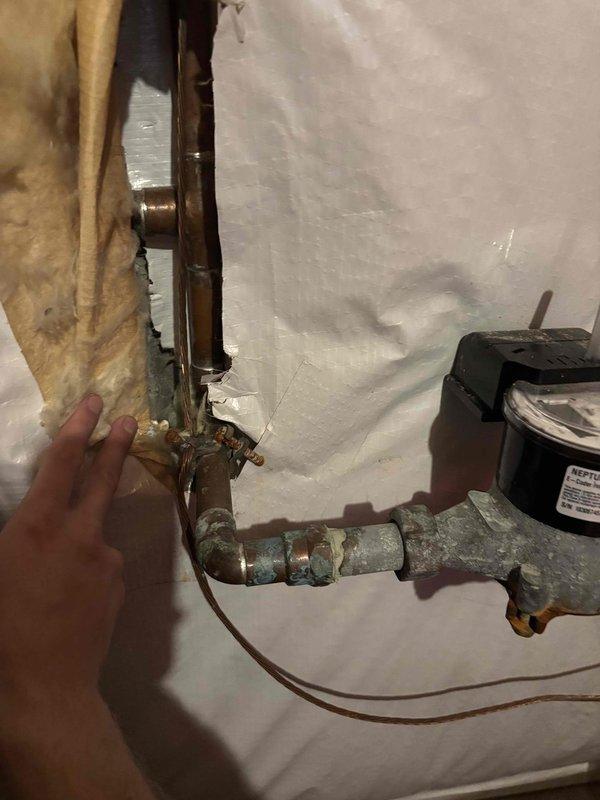 # Water Leak Service Completed

Responded to water leak investigation and performed comprehensive plumbing system inspection. Upon arrival, identified corroded copper piping with significant greenish-white patina buildup indicating long-term moisture exposure and potential leak source. Inspected horizontal and vertical pipe runs along with associated fittings and joints for integrity issues.

Documented existing plumbing configuration including water pump/valve controller assembly with cylindrical motor component and control housing. Assessed condition of copper pipe connections, elbow joints, and various fittings throughout the system. Noted advanced corrosion on horizontal pipe sections requiring attention.

Established containment area with protective plastic sheeting to prevent water damage during inspection and repair work. Evaluated electronic control device and associated wiring for proper operation. Identified compromised pipe sections showing deterioration and patina formation