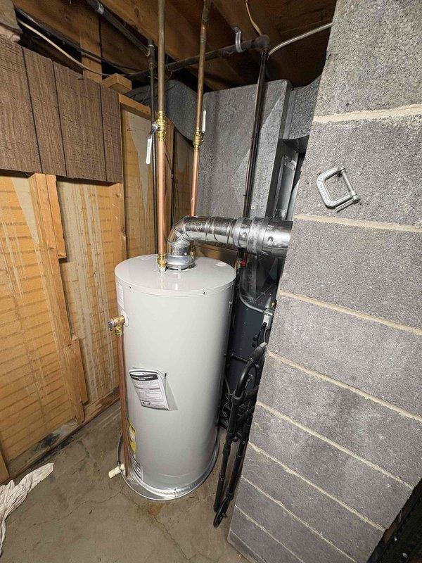 Completed installation of 40-gallon natural gas water heater with 6-inch vent and short configuration in basement utility area. Unit was positioned against cinder block wall with proper copper supply line connections, brass fittings, and metallic venting installed to manufacturer specifications. All plumbing connections were secured and tested for proper operation.