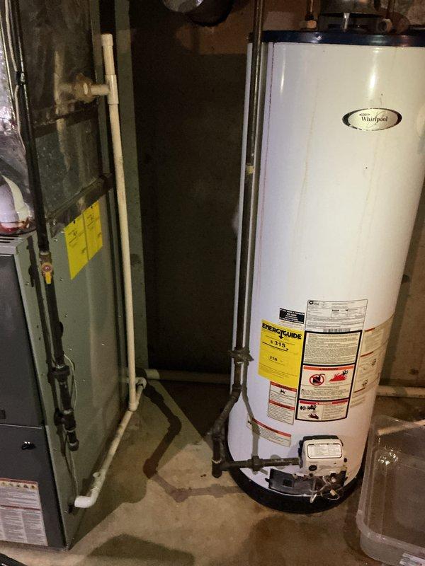 Responded to reported water heater leak and performed diagnostic inspection of Whirlpool residential tank-style water heater. Upon arrival, documented equipment specifications and assessed unit condition, noting visible moisture on concrete floor near base of water heater. Photographed manufacturer data plate and equipment labels for service records and confirmed water heater model and age information.