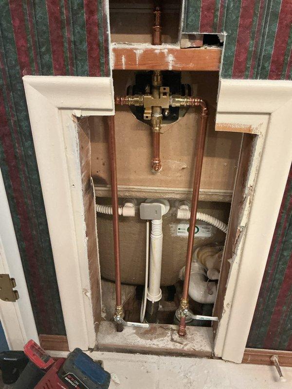 Accessed wall cavity to remove existing shower valve assembly and install new Delta shower valve. Cut and secured drywall opening to expose plumbing infrastructure, disconnected old brass valve assembly, and installed replacement valve with proper connections to existing copper supply lines. Tested system for proper operation and water flow, reassembled chrome trim including shower arm, escutcheon plate, and tub spout. Verified no leaks at connections and confirmed drain mechanism functionality before completing installation.
