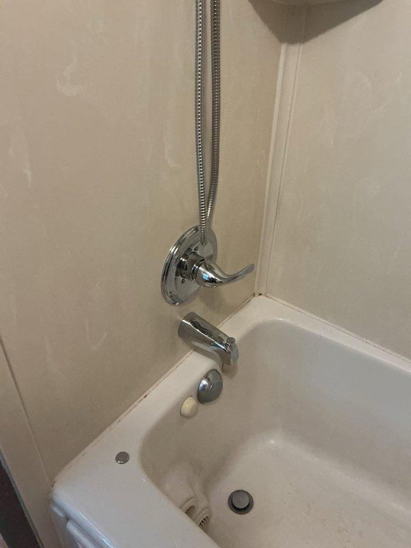 Accessed wall cavity to remove existing shower valve assembly and install new Delta shower valve. Cut and secured drywall opening to expose plumbing infrastructure, disconnected old brass valve assembly, and installed replacement valve with proper connections to existing copper supply lines. Tested system for proper operation and water flow, reassembled chrome trim including shower arm, escutcheon plate, and tub spout. Verified no leaks at connections and confirmed drain mechanism functionality before completing installation.