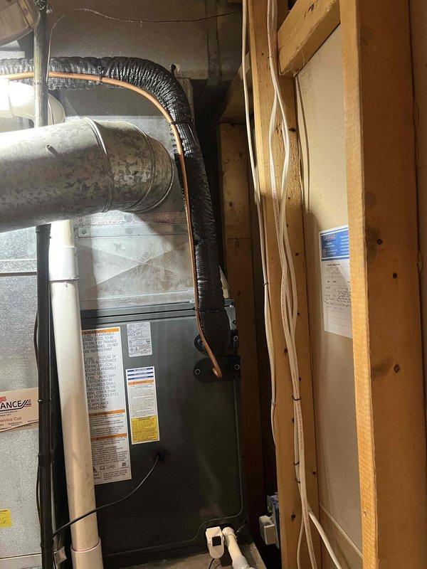 Successfully completed full air conditioning system replacement in residential utility space. Installed new furnace unit with proper ductwork connections, including metallic supply plenum and flexible black ribbed return ductwork. Configured all refrigerant line sets, electrical connections, and condensate drain lines per manufacturer specifications. Verified all safety labels and warning stickers are visible and properly affixed to equipment. System tested and operational upon completion.