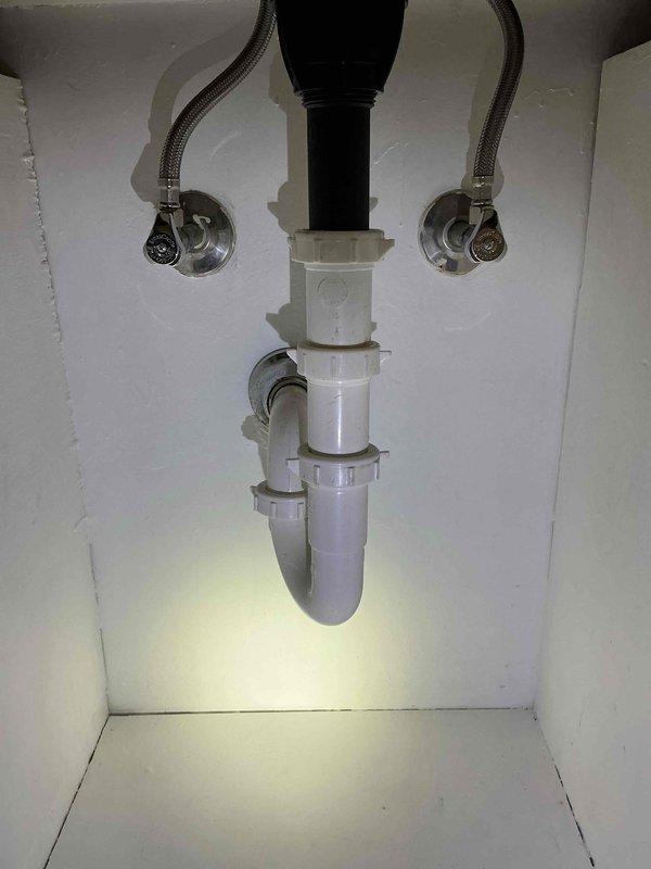 Replaced bathroom faucet with new two-handle brushed nickel fixture featuring lever handles and central spout mounted on rectangular base plate. Verified proper installation of braided stainless steel supply lines connected to shut-off valves and confirmed P-trap drain assembly functioning correctly with no leaks detected.