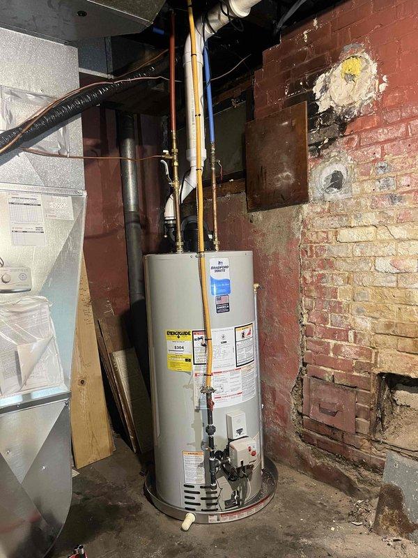 Successfully completed water heater installation in basement utility area. Removed existing unit and installed new white cylindrical water heater against exposed brick wall. Connected copper supply lines to building's plumbing system and ensured proper integration with existing infrastructure. Verified all manufacturer specifications and safety requirements were met. Tested unit operation and confirmed proper functionality of all connections. Installation completed within scheduled timeframe with system fully operational upon departure.