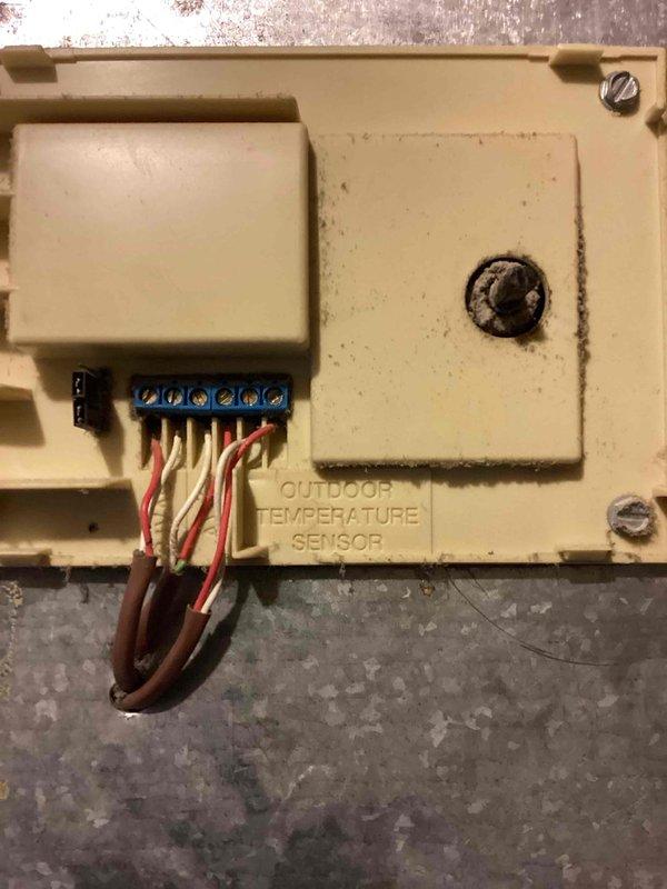 Completed annual heating and cooling maintenance on EnergiAir system under 3-year warranty coverage extending through June 2028. Performed comprehensive tune-up including inspection of control board with TEST/TWIN functionality, verified proper operation of all electrical connections and terminal blocks, and confirmed illuminated orange LED indicator showing active system status. Inspected outdoor temperature sensor mounted on exterior wall, verified wiring connections at blue terminal block with brown, white, and red-striped conductors intact and secure. Documented system components and wiring configuration through photographic records for warranty compliance and future service reference.