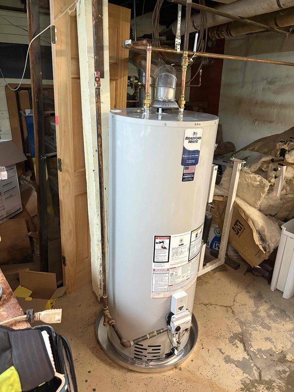 Responded to emergency water heater replacement estimate for a leaking 50-gallon natural gas Sears unit (Model 153.332550) manufactured in 1994. Upon inspection, confirmed active leak requiring immediate replacement due to age and deterioration of the tank, with visible corrosion noted on warranty plate and unit showing nearly 30 years of service life exceeding typical operational lifespan. Documented existing installation configuration including copper supply line connections, pressure relief valve assembly, and current placement on concrete pad in basement utility area, and provided comprehensive estimate for new water heater installation.