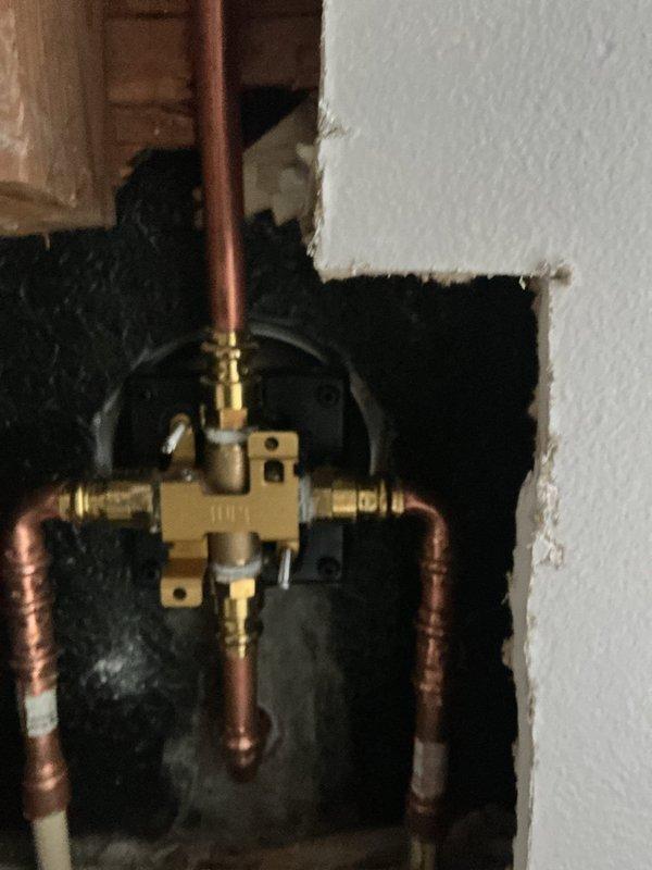Replaced existing shower valve with new brass valve assembly. Accessed plumbing through wall opening, removed old valve, installed new valve with proper copper pipe connections and mounting flange, and verified system integrity. Property was vacant during service.