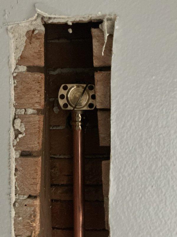 Replaced existing shower valve with new brass valve assembly. Accessed plumbing through wall opening, removed old valve, installed new valve with proper copper pipe connections and mounting flange, and verified system integrity. Property was vacant during service.