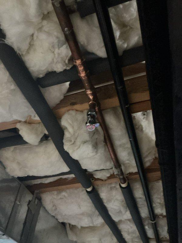 Responded to water leak service call for pinhole leak on copper water line supplying ice maker. Located leak in attic space on vertical copper supply line running through insulated wall cavity. Repaired damaged section of copper piping and verified system integrity. Tested water flow to ice maker connection and confirmed no additional leaks present after repair completion.