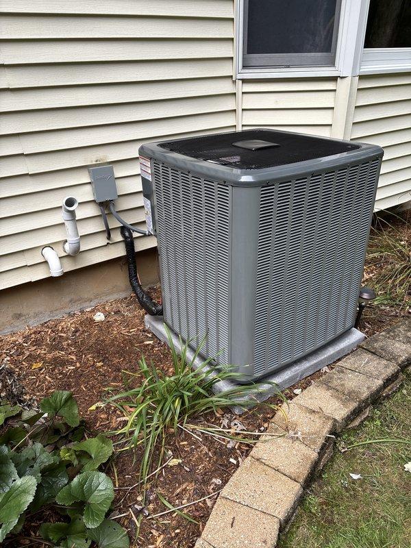 Completed full residential HVAC system installation including new furnace and air conditioning condenser unit. Installed gray metal furnace in basement with proper venting using white PVC piping, connected to new ductwork system with Y-branch configurations extending to existing trunk lines. Mounted outdoor AC condenser on concrete pad against exterior wall with beige vinyl siding, installed refrigerant line set with black insulation running from outdoor unit to indoor coil, and completed electrical connections with disconnect box mounted on exterior wall. Verified all connections, tested system operation, and confirmed proper airflow through ductwork. Installation completed per manufacturer specifications with all components operational.