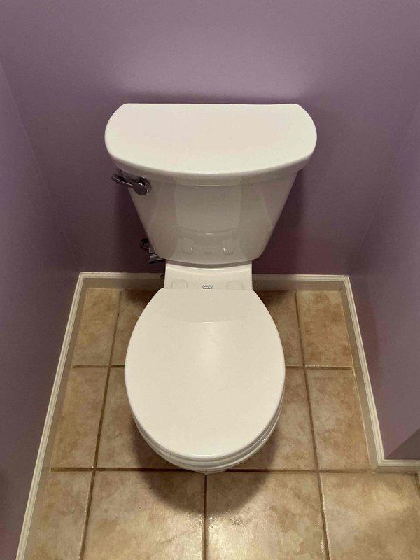 Responded to complaint of water leaking from fill valve during toilet flush cycle. Upon arrival, removed tank lid and inspected internal flush mechanism on American Standard two-piece toilet. Identified faulty fill valve assembly with red cap causing water discharge from top of valve during refill operation. Replaced defective fill valve with new unit, reconnected refill tube to overflow pipe, and adjusted water level to manufacturer specifications. Cycled flush mechanism multiple times to verify proper operation and confirm no leakage from valve assembly. Tank now refills correctly without water spraying from top of fill valve. Photographed completed repair for service records. Unit tested and returned to normal operation.